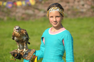 A young bird of prey sitting on the girl's hand in the spring .Falcon. Peregrine. Balaban