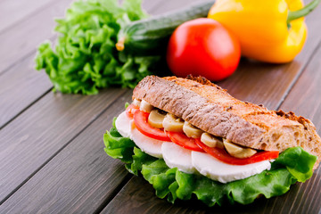 Fresh vegetables and salad lie behind wholemeal bread sandwich