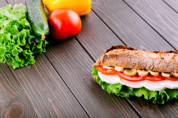 Fresh vegetables and salad lie behind wholemeal bread sandwich