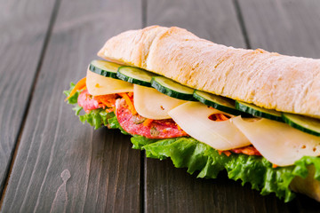 Crusty wholemeal bread sandwich with cucumbers, cheese, salami and green salad