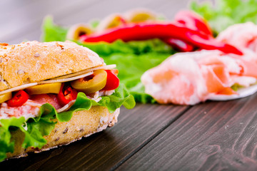 Sandwich made of wholemeal bread, olives, meat and green salad