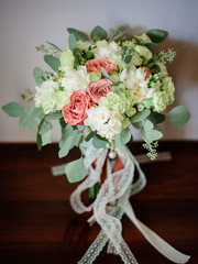 White wedding bouquet twined with lace ribbons stands on wooden table