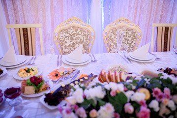 Chairs with golden design stand at dinner table served for wedding couple