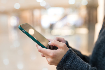 Woman sending sms on mobile phone in shopping mall
