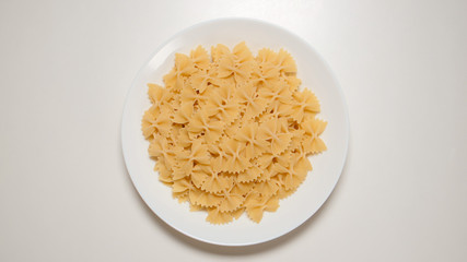 TOP VIEW: Bow noodles on a white dish on a white table