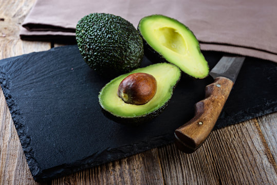 Fresh cutting avocado on stone board over wooden background