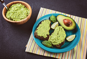 Avocado spread. Fresh sliced avocado and guacamole on dark background