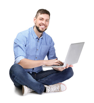 Handsome young programmer with laptop on color background