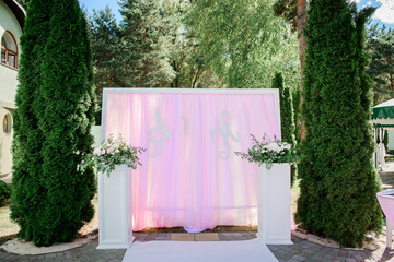 Wedding altar made of pink cloth in white frame and pillars with flowers before it