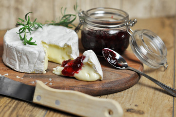 Delicious camembert cheese with cranberry on wooden background