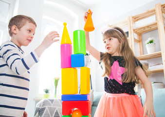 Siblings playing with colorful blocks at home, happy family