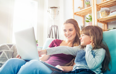Fototapeta premium Mother and daughter using laptop together, happy loving family