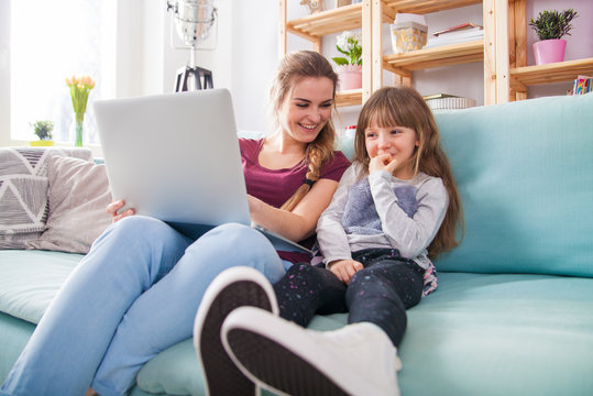 Mother and daughter using laptop together, happy loving family