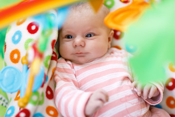 Cute adorable newborn baby playing on colorful toy gym