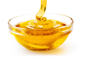 close up of honey dropping into a glass bowl isolated on white background