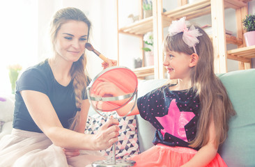 Mother and daughter playing and doing makeup, family at home