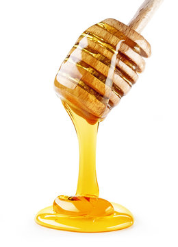 close up of honey dripping from a wooden dipper isolated on white background
