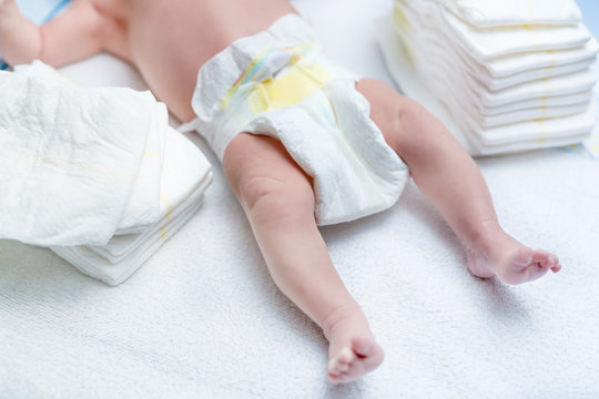 Feet of newborn baby on changing table with diapers