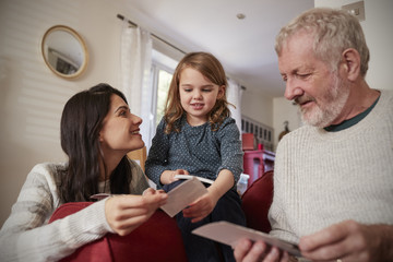Multi Generation Family At Home Looking At Photographs