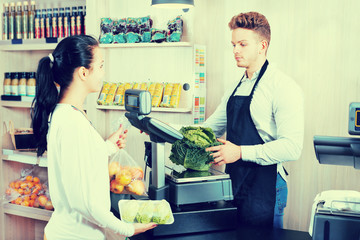 Male assistant helping customer in grocery shop