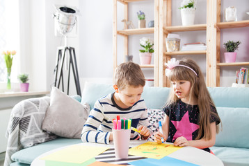 Brother and sister drawing with colorful pencils at home