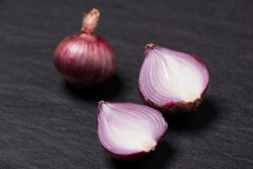 Full and half cut spanish onions on dark background.