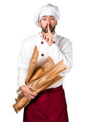 Young baker holding some bread and making silence gesture