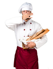 Young baker holding some bread a making smelling bad gesture