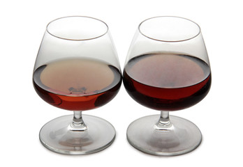 Glass with brandy and whiskey on white background