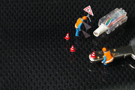 The damaged lan connection cable plug and maintenance figure miniature model represent the computor business and technology concept related idea.  - Powered by Adobe