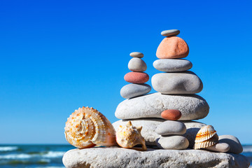 Pyramid of colorful rocks and shells on the sea background. The concept of peace and harmony