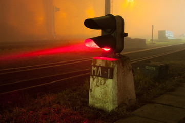 Semaphore on the railway in the fog at night, glowing red, gloomy scene