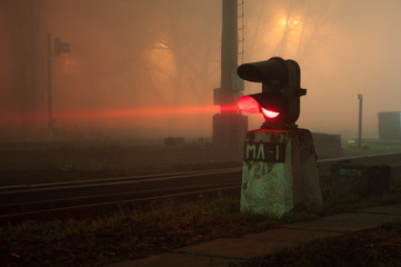 Semaphore on the railway in the fog at night, glowing red. Gloomy scene