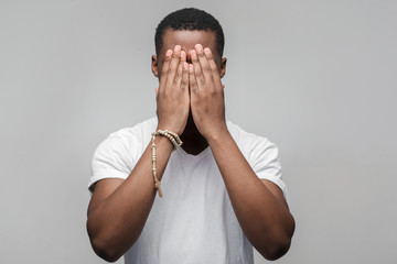 Depressed african american man with hands on face. Unhappy guy bothered by mistakes....