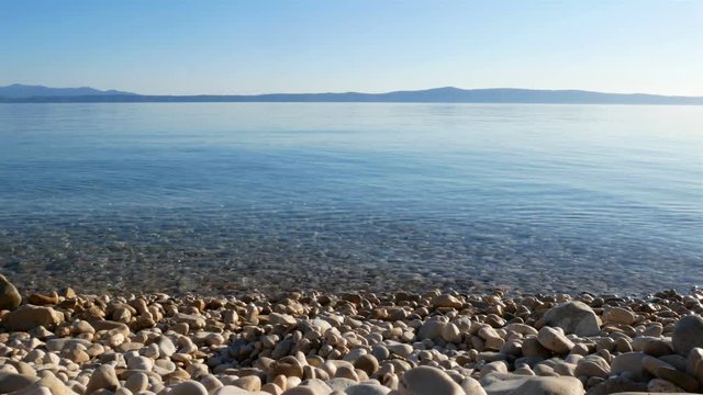 Pebble beach and crystal clear blue Adriatic sea landscape on sunny day