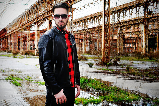 young trendy man with leather jacket, red shirt and black pants with low  waist. background metropolitan Stock Photo | Adobe Stock
