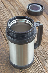 Thermos flask mug with lid on wooden table