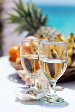 Wedding rings on seashell and glass of champagne