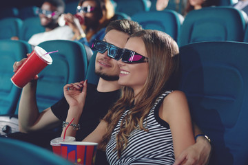 Boyfriend and gifrliend in modern cinema watching film.