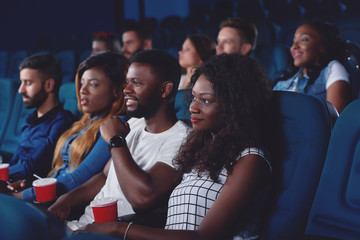 Friends watching movie in modern cinema hall.