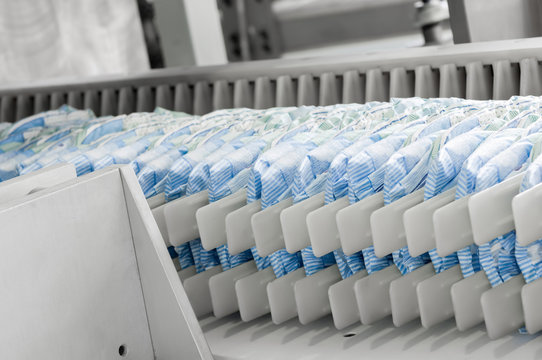 diapers on a conveyor belt closeup. factory and equipment for the production of pampers