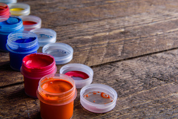  jars with colorful gouache paints on wooden background