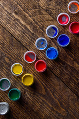 jars with colorful gouache paints on wooden background