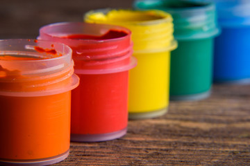  jars with colorful gouache paints on wooden background