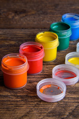  jars with colorful gouache paints on wooden background