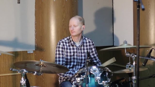 Handsome guy behind the drum kit in shirt and trousers plays the drums