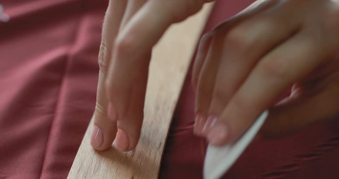A close-up of girl's hand designer line charting on the fabric using patterns