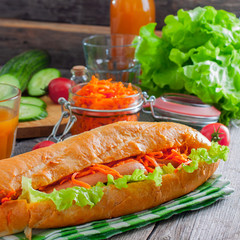 Hot dog with sausage, carrots and sauce, selective focus, square