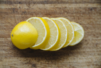 Yellow juicy lemon cut in pieces on a wooden table background
