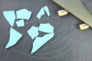 The cracked and broken pieces of concrete wall arrangement in to the world map shape put beside the wing part of plastic model toy plane represent the world and logistic business concept related idea.